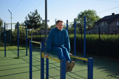 A dedicated young athlete puts in the hard work, vigorously training on gym equipment outdoors to prepare his body. He builds strength and endurance before hitting the field or court for competition