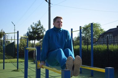 A dedicated young athlete puts in the hard work, vigorously training on gym equipment outdoors to prepare his body. He builds strength and endurance before hitting the field or court for competition