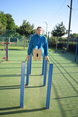 A dedicated young athlete puts in the hard work, vigorously training on gym equipment outdoors to prepare his body. He builds strength and endurance before hitting the field or court for competition
