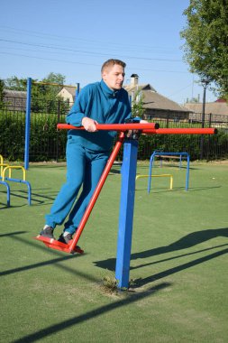 A dedicated young athlete puts in the hard work, vigorously training on gym equipment outdoors to prepare his body. He builds strength and endurance before hitting the field or court for competition