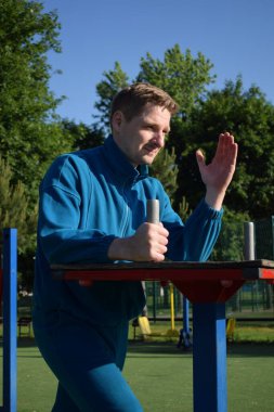 A dedicated young athlete puts in the hard work, vigorously training on gym equipment outdoors to prepare his body. He builds strength and endurance before hitting the field or court for competition