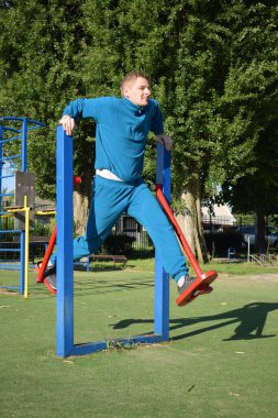A dedicated young athlete puts in the hard work, vigorously training on gym equipment outdoors to prepare his body. He builds strength and endurance before hitting the field or court for competition
