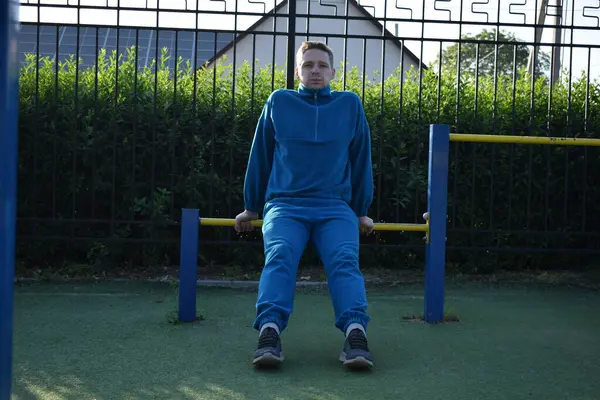 A dedicated young athlete puts in the hard work, vigorously training on gym equipment outdoors to prepare his body. He builds strength and endurance before hitting the field or court for competition