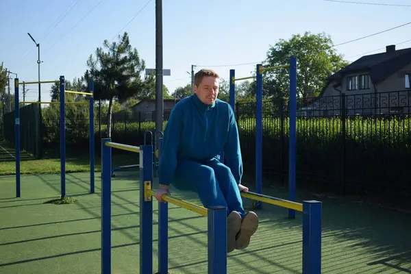 A dedicated young athlete puts in the hard work, vigorously training on gym equipment outdoors to prepare his body. He builds strength and endurance before hitting the field or court for competition