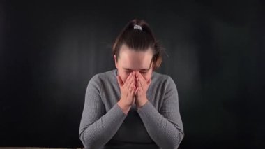 İçerideki siyah arka planda hapşıran gri kazaklı genç bir kadının portresi. Hastalık, soğuk algınlığı ya da alerjiden kaynaklanan bir hapşırığın vücut tepkisi. Sağlık ve solunum sorunları