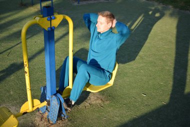 A dedicated young athlete puts in the hard work, vigorously training on gym equipment outdoors to prepare his body. He builds strength and endurance before hitting the field or court for competition