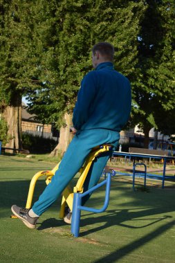 A dedicated young athlete puts in the hard work, vigorously training on gym equipment outdoors to prepare his body. He builds strength and endurance before hitting the field or court for competition