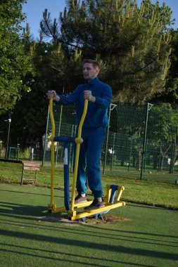 A dedicated young athlete puts in the hard work, vigorously training on gym equipment outdoors to prepare his body. He builds strength and endurance before hitting the field or court for competition