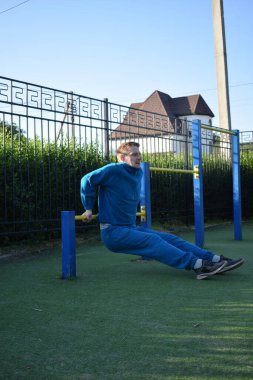 A dedicated young athlete puts in the hard work, vigorously training on gym equipment outdoors to prepare his body. He builds strength and endurance before hitting the field or court for competition