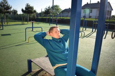 A dedicated young athlete puts in the hard work, vigorously training on gym equipment outdoors to prepare his body. He builds strength and endurance before hitting the field or court for competition