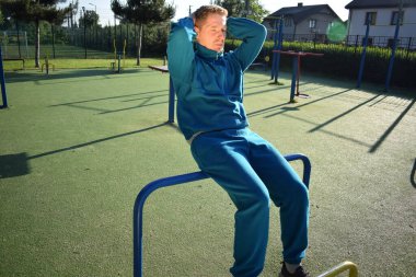 A dedicated young athlete puts in the hard work, vigorously training on gym equipment outdoors to prepare his body. He builds strength and endurance before hitting the field or court for competition