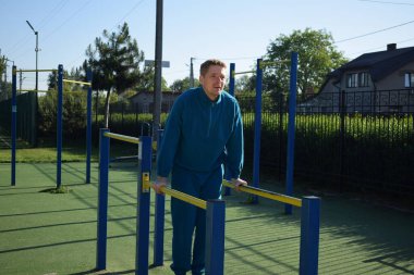 A dedicated young athlete puts in the hard work, vigorously training on gym equipment outdoors to prepare his body. He builds strength and endurance before hitting the field or court for competition