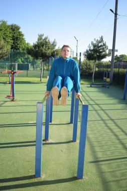 A dedicated young athlete puts in the hard work, vigorously training on gym equipment outdoors to prepare his body. He builds strength and endurance before hitting the field or court for competition
