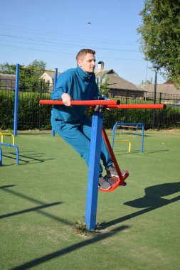 A dedicated young athlete puts in the hard work, vigorously training on gym equipment outdoors to prepare his body. He builds strength and endurance before hitting the field or court for competition