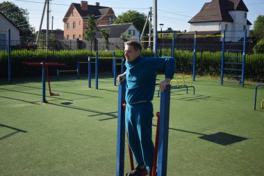 A dedicated young athlete puts in the hard work, vigorously training on gym equipment outdoors to prepare his body. He builds strength and endurance before hitting the field or court for competition