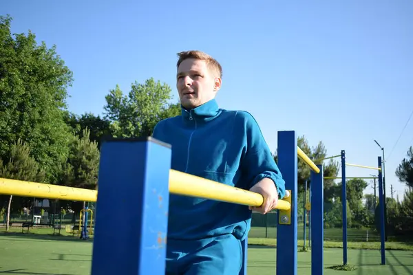 Stock image A dedicated young athlete puts in the hard work, vigorously training on gym equipment outdoors to prepare his body. He builds strength and endurance before hitting the field or court for competition