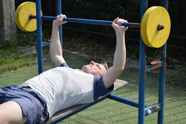 A dedicated young athlete puts in the hard work, vigorously training on gym equipment outdoors to prepare his body. He builds strength and endurance before hitting the field or court for competition