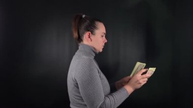 Gösterişli genç bir kadın hevesle bir tomar para sayıyor. Basit bir siyah fon üzerinde hayat değiştiren bir şans vuruşunun heyecanı. Kutlama sevincinin simgesi.