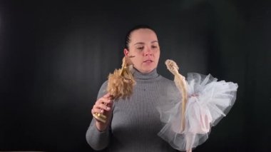 Kuklalarla oynayan çekici beyaz bir kadının portresi. Kuklacı, kukla gösterisi, siyah arka plandaki kuklaları tasvir ediyor. Cansız karakterler aracılığıyla yaratıcı hikaye anlatımı
