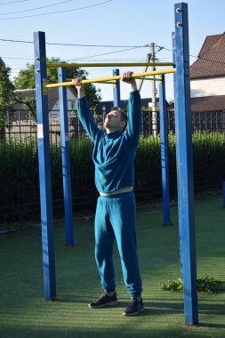 A dedicated young athlete puts in the hard work, vigorously training on gym equipment outdoors to prepare his body. He builds strength and endurance before hitting the field or court for competition