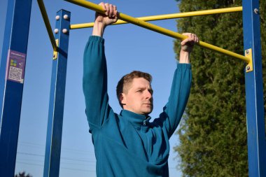 A dedicated young athlete puts in the hard work, vigorously training on gym equipment outdoors to prepare his body. He builds strength and endurance before hitting the field or court for competition
