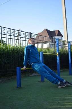 A dedicated young athlete puts in the hard work, vigorously training on gym equipment outdoors to prepare his body. He builds strength and endurance before hitting the field or court for competition