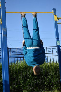 A dedicated young athlete puts in the hard work, vigorously training on gym equipment outdoors to prepare his body. He builds strength and endurance before hitting the field or court for competition