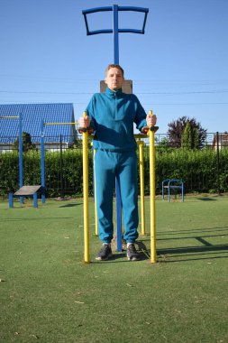 A dedicated young athlete puts in the hard work, vigorously training on gym equipment outdoors to prepare his body. He builds strength and endurance before hitting the field or court for competition