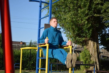 A dedicated young athlete puts in the hard work, vigorously training on gym equipment outdoors to prepare his body. He builds strength and endurance before hitting the field or court for competition