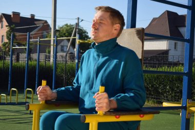 A dedicated young athlete puts in the hard work, vigorously training on gym equipment outdoors to prepare his body. He builds strength and endurance before hitting the field or court for competition