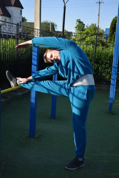 A dedicated young athlete puts in the hard work, vigorously training on gym equipment outdoors to prepare his body. He builds strength and endurance before hitting the field or court for competition