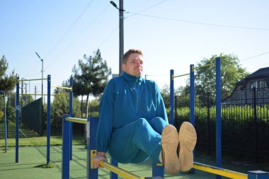 A dedicated young athlete puts in the hard work, vigorously training on gym equipment outdoors to prepare his body. He builds strength and endurance before hitting the field or court for competition