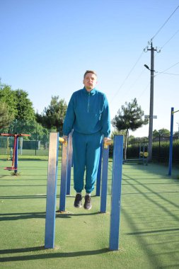 A dedicated young athlete puts in the hard work, vigorously training on gym equipment outdoors to prepare his body. He builds strength and endurance before hitting the field or court for competition