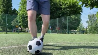 Spor giyimli genç bir adam sabah futbol sahasında antrenman yapıyor. Spor için adanmışlık ve tutku, sabah egzersizinin özü ve açık havada pratik.