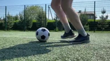 Spor giyimli genç bir adam sabah futbol sahasında antrenman yapıyor. Spor için adanmışlık ve tutku, sabah egzersizinin özü ve açık havada pratik.