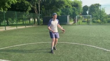 Spor giyim sektöründe genç bir adam sabah bir spor sahasında badminton oynuyor. Spor için adanmışlık ve tutku, sabah egzersizinin özü ve açık havada pratik.