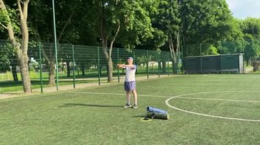 Spor giyim sektöründe genç bir adam sabah spor sahasında spor aleti kullanarak spor yapıyor. Forma olan bağlılığı odaklanma ve enerjiyle eğitim rutinini gerçekleştiriyor.