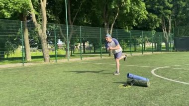 Spor giyim sektöründe genç bir adam sabah spor sahasında spor aleti kullanarak spor yapıyor. Forma olan bağlılığı odaklanma ve enerjiyle eğitim rutinini gerçekleştiriyor.