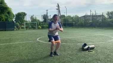 Spor giyim sektöründe genç bir adam sabah spor sahasında spor aleti kullanarak spor yapıyor. Forma olan bağlılığı odaklanma ve enerjiyle eğitim rutinini gerçekleştiriyor.