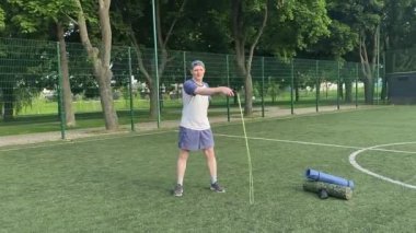 Spor giyim sektöründe genç bir adam sabah spor sahasında spor aleti kullanarak spor yapıyor. Forma olan bağlılığı odaklanma ve enerjiyle eğitim rutinini gerçekleştiriyor.