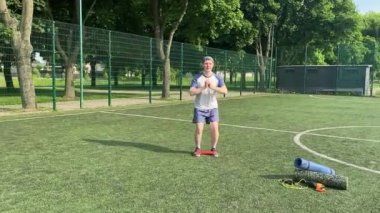 Spor giyim sektöründe genç bir adam sabah spor sahasında spor aleti kullanarak spor yapıyor. Forma olan bağlılığı odaklanma ve enerjiyle eğitim rutinini gerçekleştiriyor.