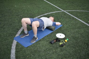 Spor giyim sektöründe genç bir adam sabah spor sahasında spor aleti kullanarak spor yapıyor. Forma olan bağlılığı odaklanma ve enerjiyle eğitim rutinini gerçekleştiriyor.