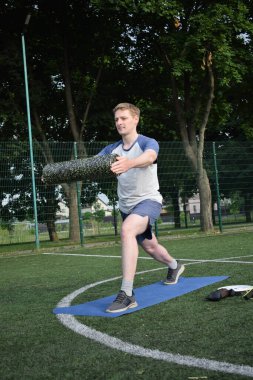 Spor giyim sektöründe genç bir adam sabah spor sahasında spor aleti kullanarak spor yapıyor. Forma olan bağlılığı odaklanma ve enerjiyle eğitim rutinini gerçekleştiriyor.