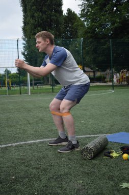 Spor giyim sektöründe genç bir adam sabah spor sahasında spor aleti kullanarak spor yapıyor. Forma olan bağlılığı odaklanma ve enerjiyle eğitim rutinini gerçekleştiriyor.