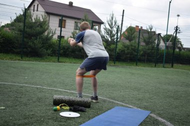 Spor giyim sektöründe genç bir adam sabah spor sahasında spor aleti kullanarak spor yapıyor. Forma olan bağlılığı odaklanma ve enerjiyle eğitim rutinini gerçekleştiriyor.
