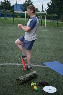 Spor giyim sektöründe genç bir adam sabah spor sahasında spor aleti kullanarak spor yapıyor. Forma olan bağlılığı odaklanma ve enerjiyle eğitim rutinini gerçekleştiriyor.