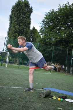 Spor giyim sektöründe genç bir adam sabah spor sahasında spor aleti kullanarak spor yapıyor. Forma olan bağlılığı odaklanma ve enerjiyle eğitim rutinini gerçekleştiriyor.