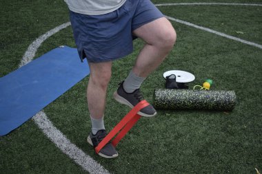 Spor giyim sektöründe genç bir adam sabah spor sahasında spor aleti kullanarak spor yapıyor. Forma olan bağlılığı odaklanma ve enerjiyle eğitim rutinini gerçekleştiriyor.