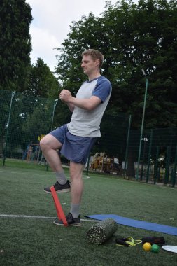 Spor giyim sektöründe genç bir adam sabah spor sahasında spor aleti kullanarak spor yapıyor. Forma olan bağlılığı odaklanma ve enerjiyle eğitim rutinini gerçekleştiriyor.