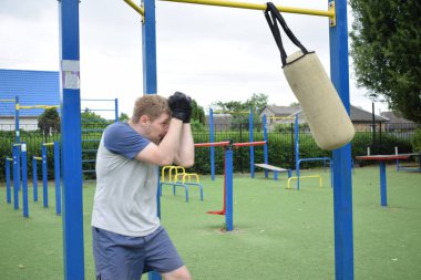 Spor giyim sektöründe genç bir adam sabah spor sahasında spor aleti kullanarak spor yapıyor. Forma olan bağlılığı odaklanma ve enerjiyle eğitim rutinini gerçekleştiriyor.